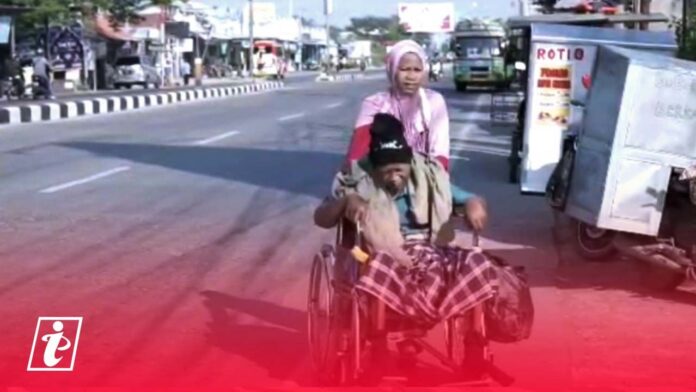 Aan Diniyaati saat berjalan mendorong kursi roda 10 Km demi membawa suaminya, Nurohman, ke rumah sakit untuk cuci darah (Gambar: panturapost.com)